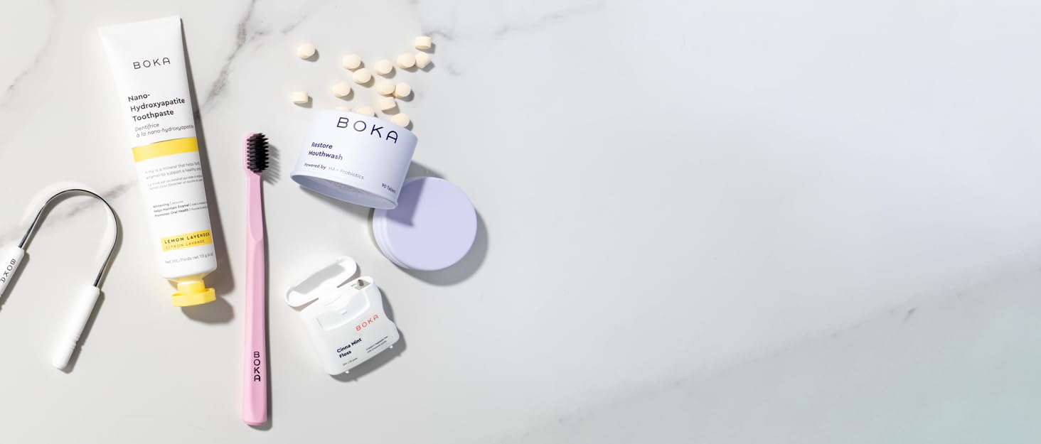 Collection of BOKA products on tile background - floss, toothpaste, toothbrush, mouthwash.