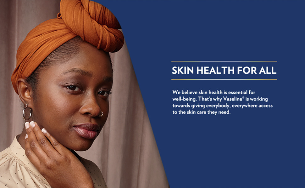 Closeup of young woman with radiant, healthy brown skin against dark blue background.