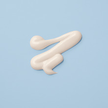 Sguiggle of white lotion on soft blue background.