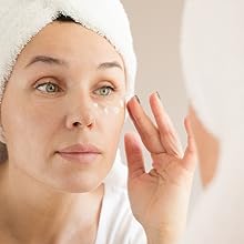 A glowing woman applying our anti-aging eye cream for women & men