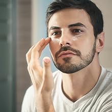 A good-looking man putting on this eye repair cream for men & women in the morning