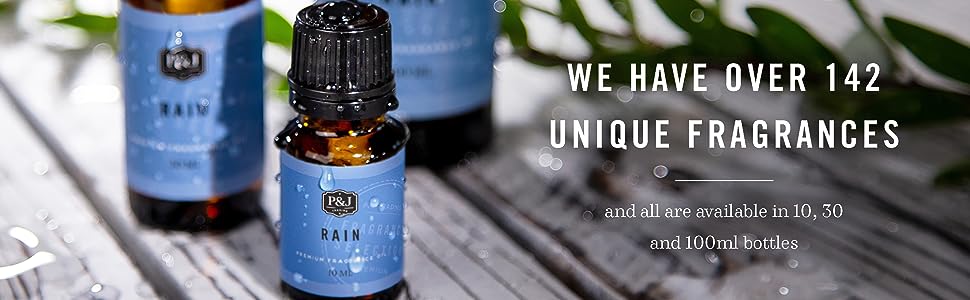 Dark amber bottle with bright blue label which read Rain Fragrance Oil on a white wood table.