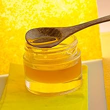 close up of a wooden spoon resting on top of an open jar of honey