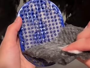 person removing dog hair from blue bath brush