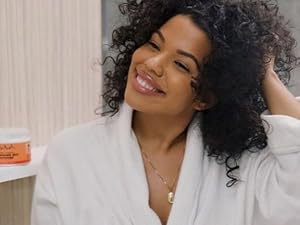 Smiling woman with curly hair wearing a white robe.