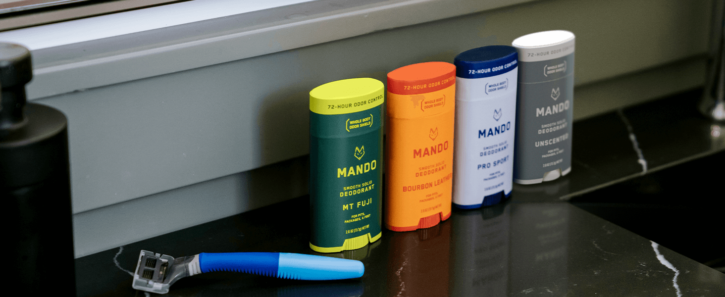 MANDO Smooth Solid Deodorants on a bathroom countertop next to a shaver