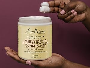 Zoomed-in image of SheaMoisture conditioner being scooped in hand against purple background.