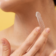 Person applying white cream to skin with fingers