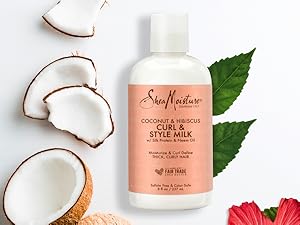 SheaMoisture Style Milk bottle with pieces of coconut and hibiscus on white background.