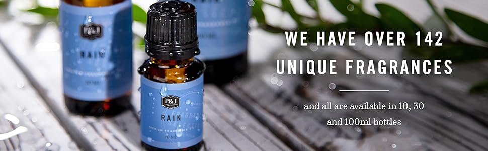 Dark amber bottle with bright blue label which read Rain Fragrance Oil on a white wood table.