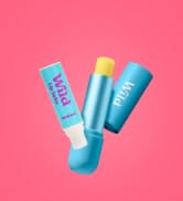 Three blue cylindrical containers with white caps against pink background. Products appear to be skincare or cosmetic items.