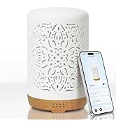 White ceramic diffuser with intricate floral cutout design. Wooden base with control buttons. Smartphone displays app interface for device control.