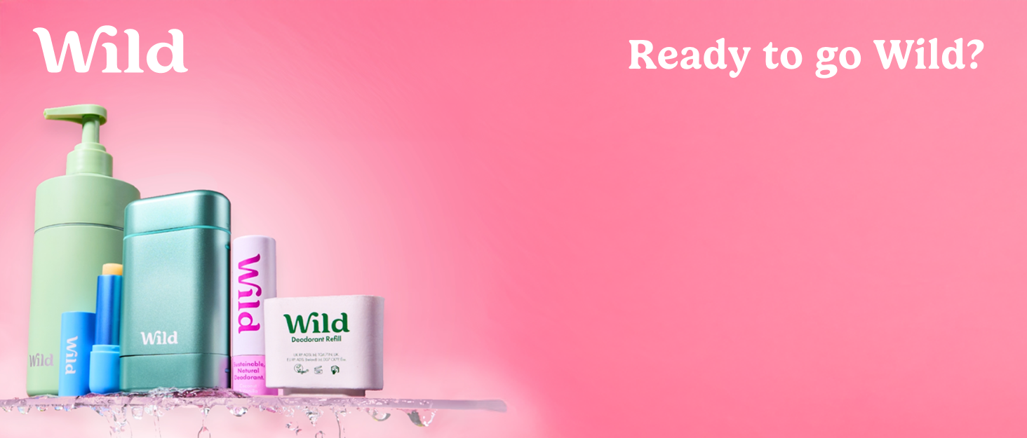 Collection of Wild branded skincare products including pastel colored bottles and containers against pink background.