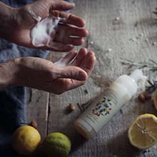 Foaming face wash in hands with lemon and lime on table