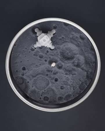 Apollo 11 Scented Candle with moon craters and miniature lunar module on the surface