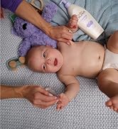Baby on a bed next to a bottle of Baby Jergens Lotion