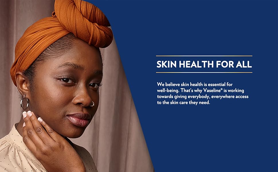 Closeup of young woman with radiant, healthy brown skin against dark blue background.