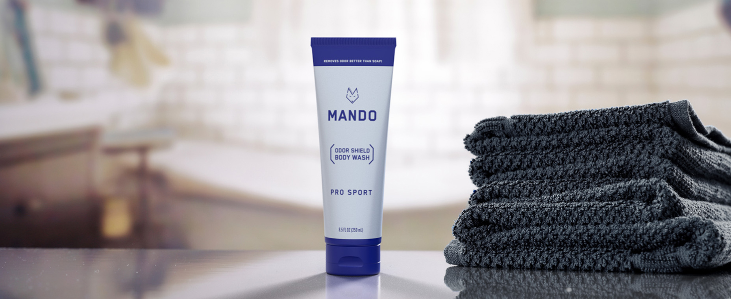 MANDO Odor Shield Body Wash in Pro Sport on a countertop next to a stack of towels