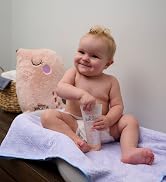 Baby sitting on changing table holding ointment