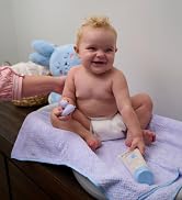 Baby on a changing table holding a bottle of skin cream