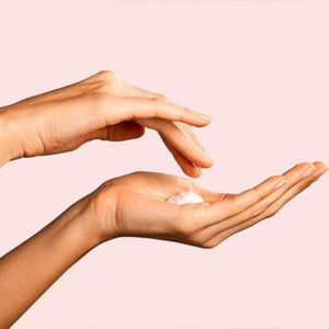 hand with cream in palm, pink background